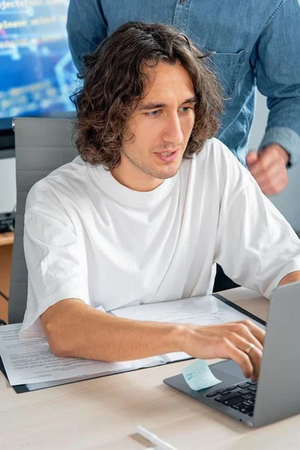 Two people browsing online clothing store on a laptop from above.